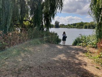 Rear view of man standing by lake against sky