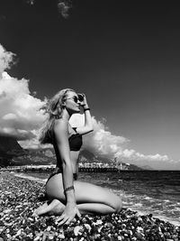 Full length of young woman on beach against sky