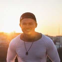 Portrait of smiling young man standing against sky during sunset