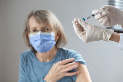 Patient looking at doctor hands holding syringe