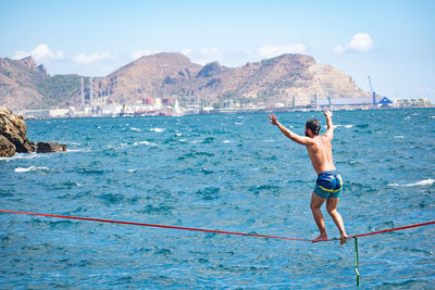 Rear view of shirtless man in sea against sky