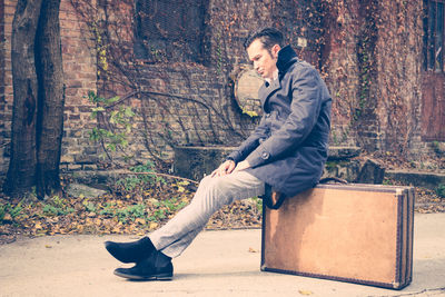 Side view of young man sitting in forest