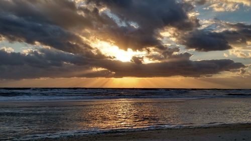 Scenic view of sea against dramatic sky during sunset