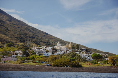 Scenic view of townscape by mountain against sky