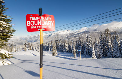 Information sign on snow covered mountain against sky