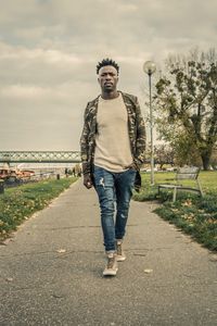 Full length portrait of young man standing against sky