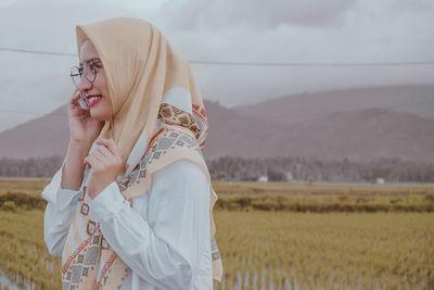 Midsection of woman standing on field against sky