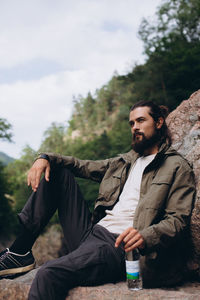 Young man sitting against sky