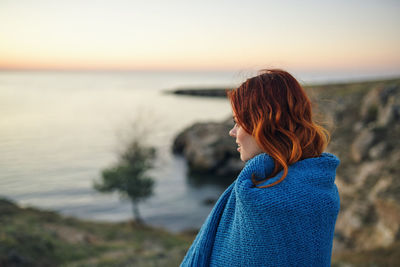 Woman looking at sea against sky during sunset