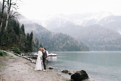 People on lake against mountains