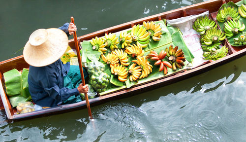 High angle view of woman with fruits on boat sailing in river