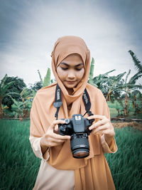 Man photographing with camera against sky