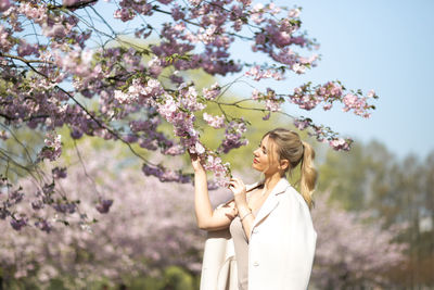 Low angle view of woman standing by flowering tree