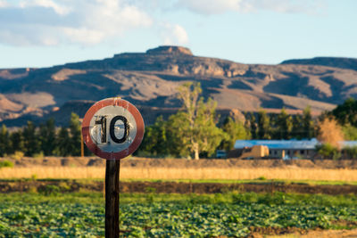 Information sign on field against sky