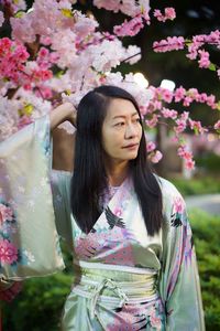 Beautiful woman standing by pink flowering plants