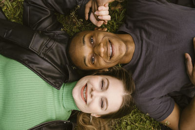 Directly above view of happy young woman and man lying on grass