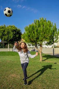 Full length of girl playing soccer ball on grass
