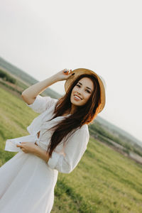 Portrait of woman standing on grass against sky