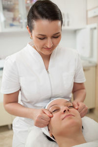 Woman giving head massage to female customer
