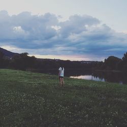 Rear view of woman walking on field against sky