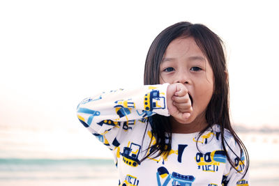 Portrait of girl yawning against sea