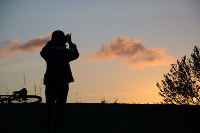 Rear view of woman against sky during sunset