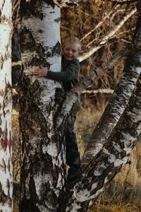 Boy standing by tree trunk