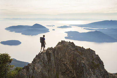 High angle view of carefree hiker with backpack on mountain against sky