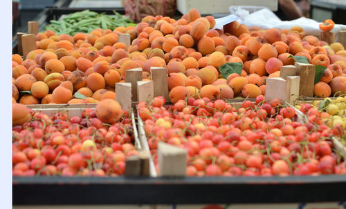 Ripe organic apricots and white cherries on green market desk in spring