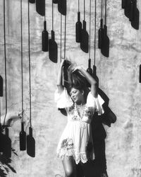 Full length of young woman standing against wall