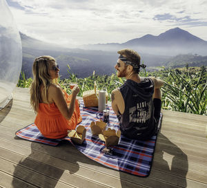 Rear view of woman sitting at restaurant against mountains