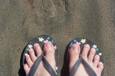 Low section of person wearing flip-flop at beach