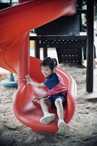 Full length of girl enjoying on red slide