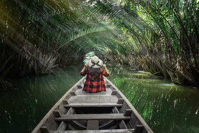 Rear view of woman standing on footbridge in forest