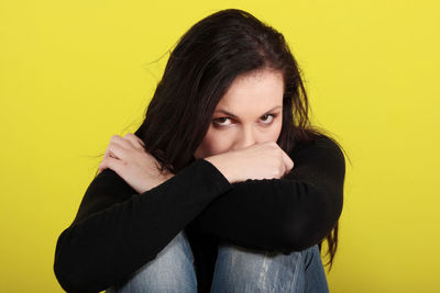 Portrait of woman against yellow background