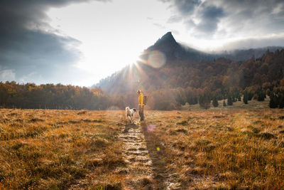 Full length of woman standing with dog on field