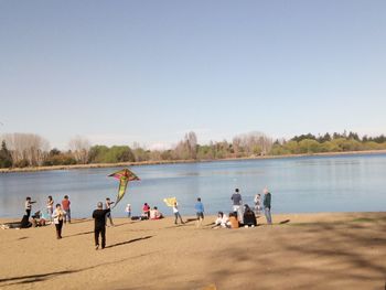 Group of people on beach against clear sky