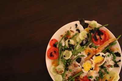 Directly above shot of boiled egg and salad in plate against black background