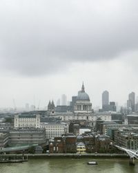 View of city at waterfront against cloudy sky