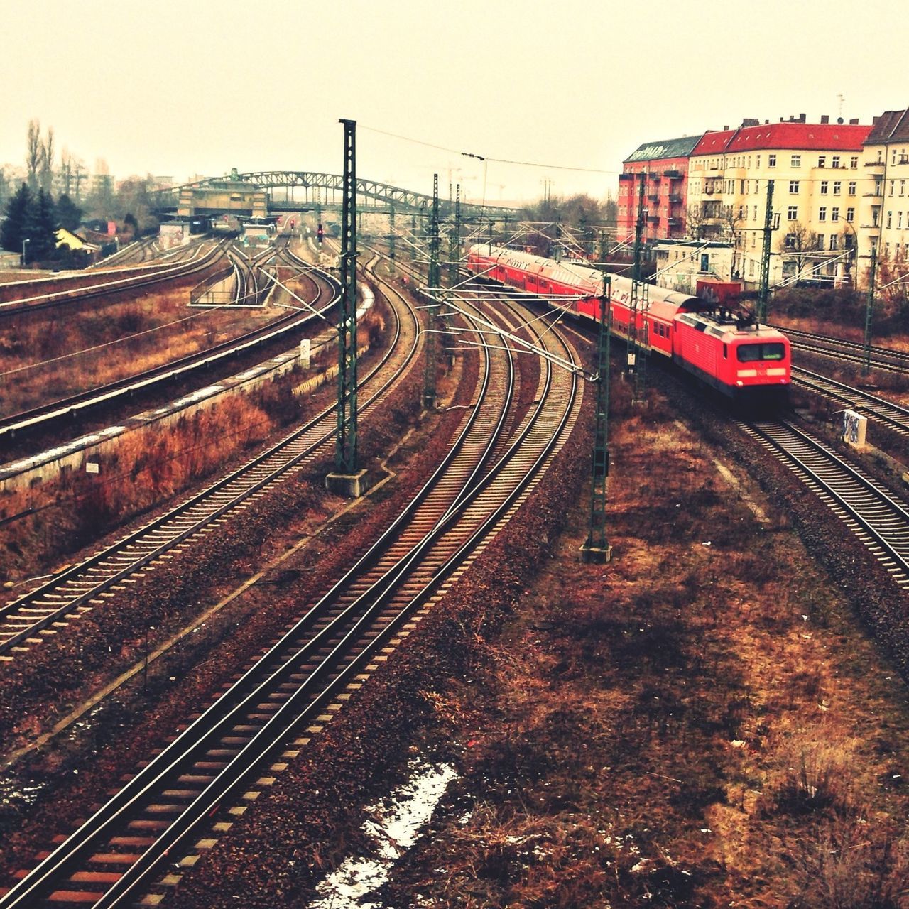 railroad track, rail transportation, transportation, public transportation, built structure, railway track, architecture, train - vehicle, railroad station, building exterior, railroad station platform, diminishing perspective, high angle view, train, the way forward, vanishing point, travel, sky, mode of transport, city