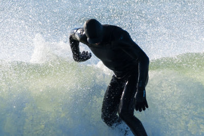 Man wearing wetsuit surfing in sea