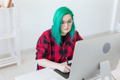 Young woman using mobile phone while sitting on table