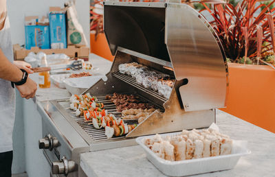 Midsection of man preparing food on barbeque grill at table