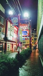 Illuminated street amidst buildings in city at night