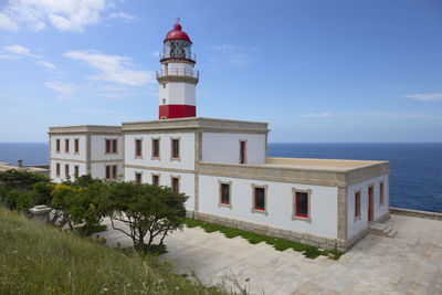 Lighthouse by sea against sky