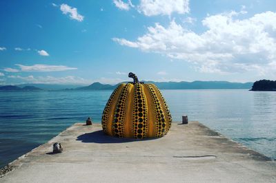 Pumpkin built structure on pier over sea against sky