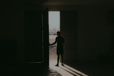 Rear view of silhouette man standing by door in building