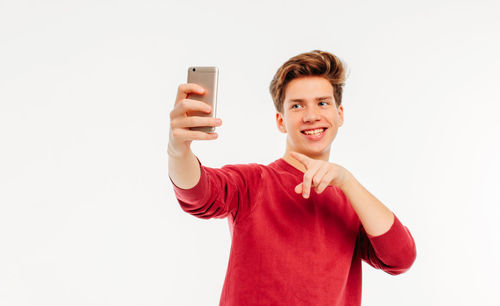 Portrait of smiling young man using smart phone against white background
