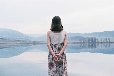 Rear view of woman standing on mountain against sky