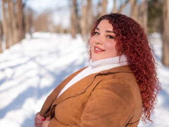 Portrait of young woman standing on snow covered field